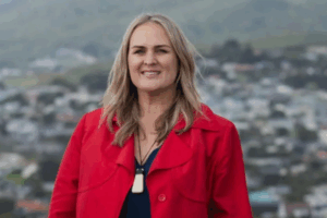 Kathleen Filo standing outdoors, smiling, with greenery in the background.
