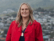Kathleen Filo standing outdoors, smiling, with greenery in the background.