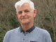 Porirua City Councillor Mike Duncan standing outdoors, smiling, with native bush in the background.
