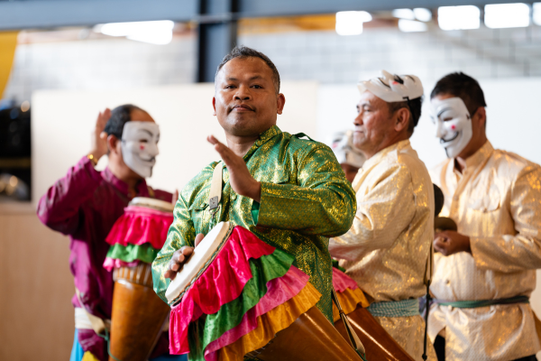Cultural Performance at Welcoming Week A group of men in traditional Southeast Asian attire perform with colourful drums and masks during a cultural celebration.