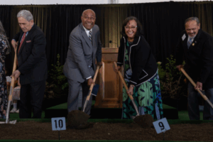 Group of dignitaries turning soil with shovels at the Wellington New Zealand Temple groundbreaking ceremony.