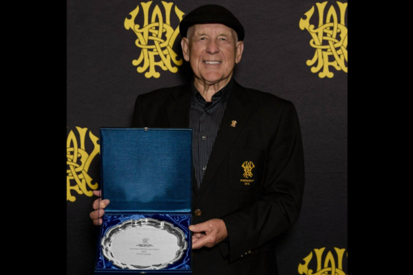 Denys Latham holding WRFU Lifetime Contribution Award in front of Wellington Rugby backdrop.