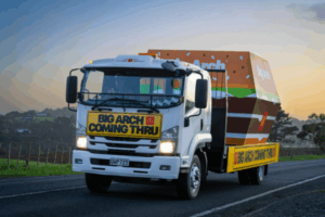 McDonald’s Big Arch promotional truck driving on a rural New Zealand road, featuring a large burger-shaped box and a sign reading "BIG ARCH COMING THRU" on the front.