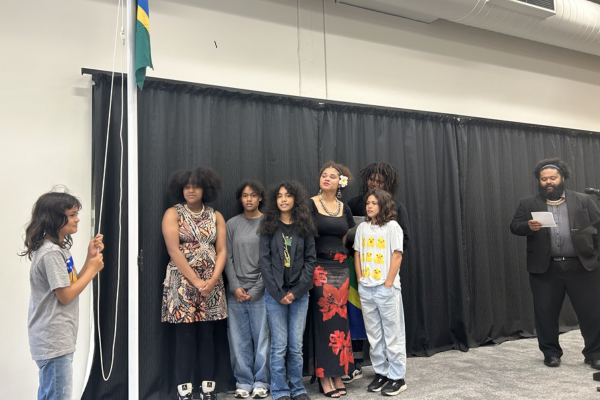 People sing next to a raised Solomon Islands flag at a cultural ceremony in Porirua.