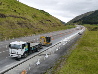 Roadworks underway on State Highway 1 Transmission Gully, with trucks, excavators, and traffic cones visible.