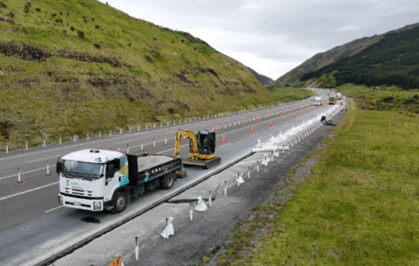 Roadworks underway on State Highway 1 Transmission Gully, with trucks, excavators, and traffic cones visible.