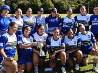 Norths Women's rugby team posing with the Eleanor Roosevelt Cup on a rugby field after their tournament win.