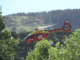 A Westpac Life Flight search and rescue helicopter flies above bush-covered hills near Paekākāriki Hill.