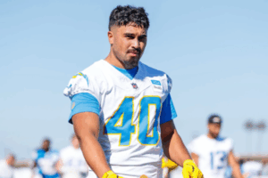 Nathaniel Salmon wears a white American football jersey with number 40 during a training session, walking on a field with other players blurred in the background.