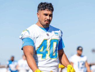 Nathaniel Salmon wears a white American football jersey with number 40 during a training session, walking on a field with other players blurred in the background.