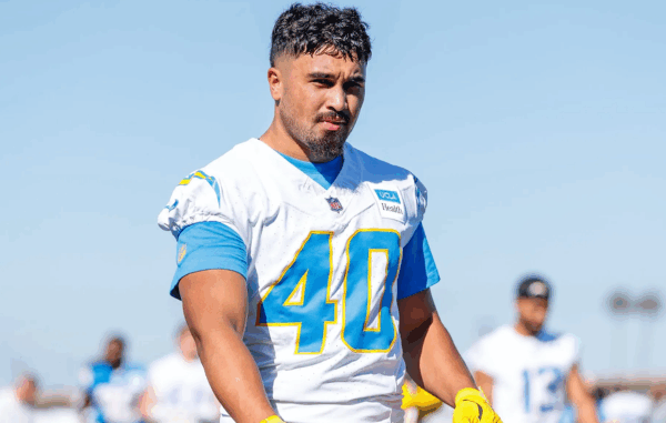 Nathaniel Salmon wears a white American football jersey with number 40 during a training session, walking on a field with other players blurred in the background.