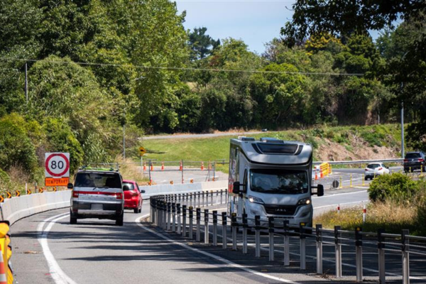Traffic moves through roadworks on Transmission Gully with cones and temporary barriers in place.