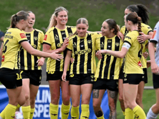 Wellington Phoenix players in yellow-and-black kits celebrate together after scoring during an A-League Women match.