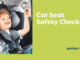 A smiling young child sits in a properly fitted car seat inside a vehicle, holding a small toy, alongside text promoting car seat safety checks.