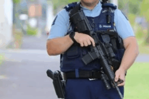 Armed New Zealand police officer holding a rifle at a street scene.