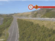 A stretch of Transmission Gully motorway at Waitangirua winds through green hills, with electronic road signs indicating a temporary 50km/h speed limit and lane closure ahead.