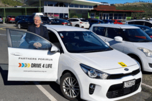Porirua City Councillor Ross Leggett standing beside a Drive 4 Life training car