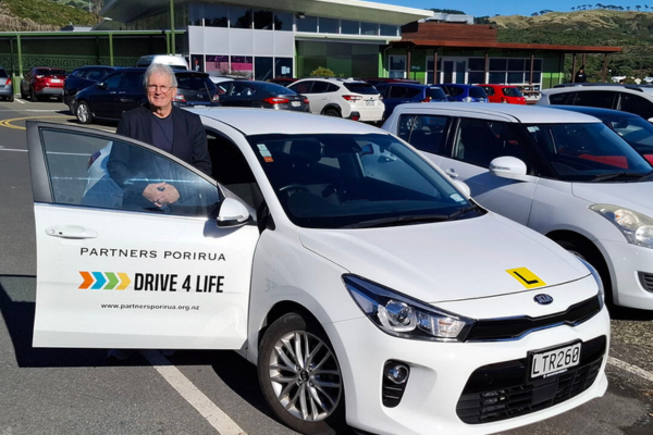 Porirua City Councillor Ross Leggett standing beside a Drive 4 Life training car