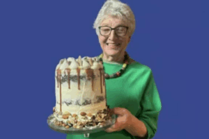 Shirley Gay smiling and holding a decorated cake