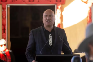 Helmut Modlik speaks at a podium during an event, addressing an audience.