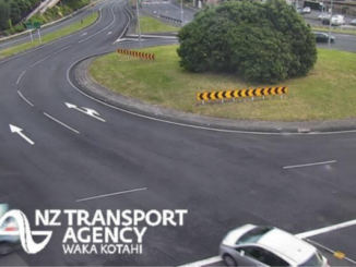 Wide view of a multi-lane roundabout interchange with light traffic and clear road markings.