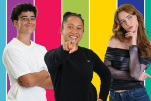 Three young people stand in front of a bright, multicoloured background. The person in the centre smiles and points directly at the camera, while the two on either side pose confidently, suggesting energy and enthusiasm.