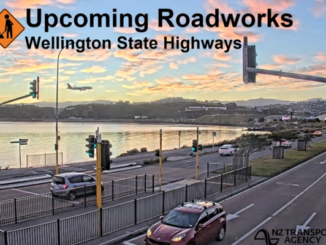 Roadworks warning graphic over a Wellington coastal highway scene, with cars travelling along a multi-lane road beside the harbour at sunset and a plane descending in the background.