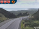 Wide view of a multi-lane highway near Porirua coastline, with light traffic travelling between hills and the sea under cloudy skies.