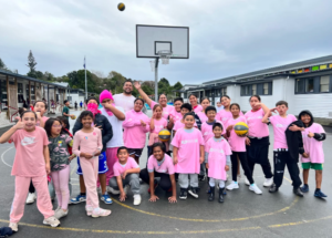 Porirua tamariki and rangatahi stand together on a school basketball court during a Ko Wai Au activity.