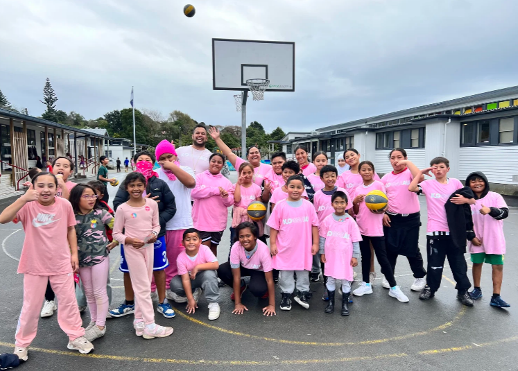 Porirua tamariki and rangatahi stand together on a school basketball court during a Ko Wai Au activity.