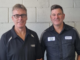 Mike and Anthony Butler standing in workshop uniforms at City Centre Motors in Porirua ahead of the business’s 50th anniversary.