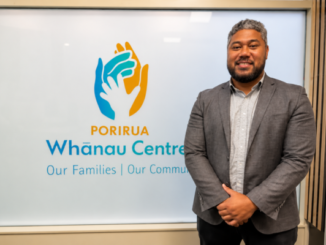 Nu'ulelei Taulalo stands beside Porirua Whānau Centre signage.