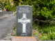 A grey stone war grave headstone for Corporal J. R. Hoare of the Wellington Regiment, partly weathered, beside a path and greenery at Porirua Cemetery.