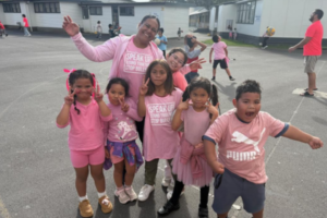 Windley School students and staff wearing pink T-shirts pose together in the playground during Pink Shirt Day celebrations in Porirua.