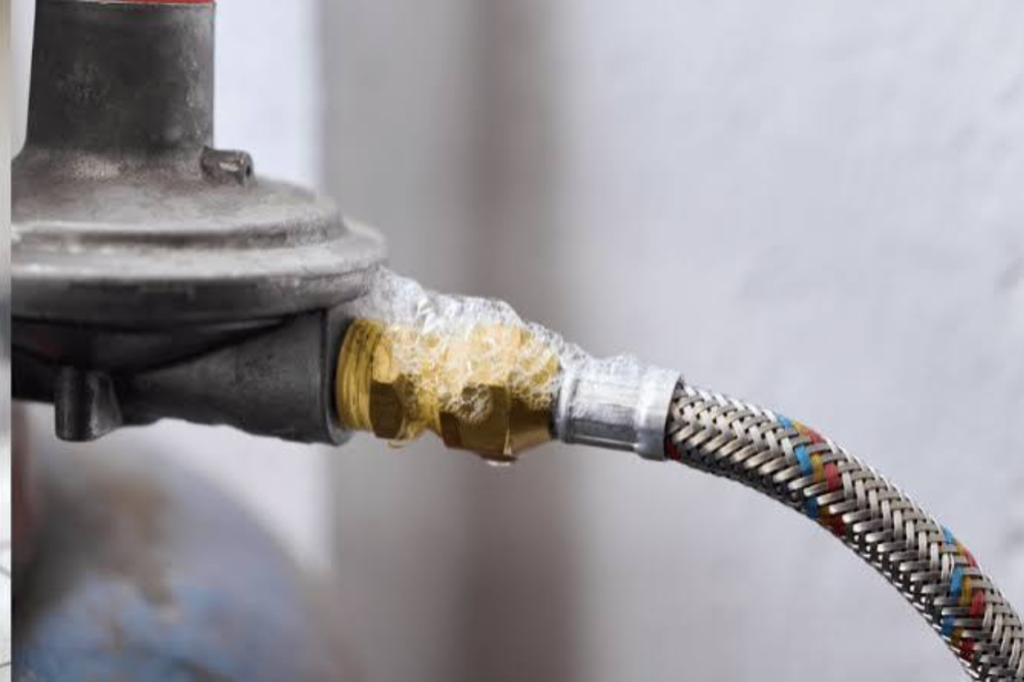 Close-up of a gas fitting and hose with bubbles around the connection.