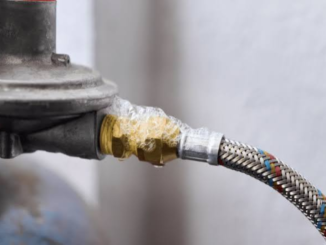 Close-up of a gas fitting and hose with bubbles around the connection.