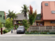 Modern affordable housing development at Our Whare Our Fale in Porirua, featuring colourful multi-storey homes, landscaped shared spaces, mature trees and residents gathered around a central community area.