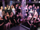 Porirua Little Theatre cast and crew gather on stage under purple and white theatre lighting after a production.