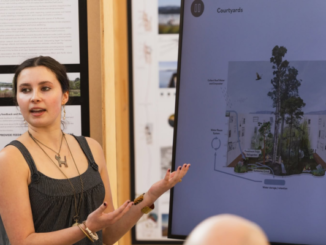 A student presents Te Manawa design concepts beside a screen showing a courtyard proposal.