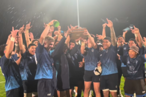 Aotea College 1st XV players celebrate under stadium lights after retaining the Beard Trophy.