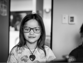 A young learner wearing new glasses after receiving a free eye exam through Painga Project’s mobile vision clinic.