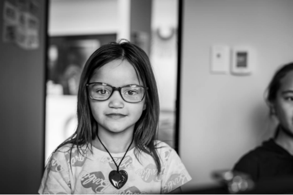 A young learner wearing new glasses after receiving a free eye exam through Painga Project’s mobile vision clinic.