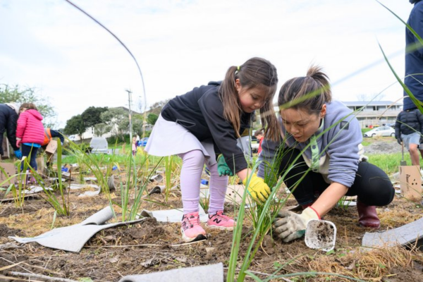 A child and an adult plant native grasses together during a community planting day.