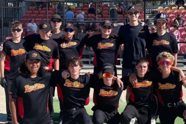 Twelve Paremata Plimmerton Softball Club members pose together in black ParePlim shirts at a softball ground.
