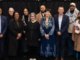 A group of 10 people, some wearing colourful garlands and one wearing a mayoral chain, stand together at the 2026 Porirua Civic Awards.