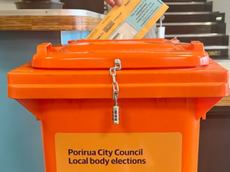 A voting paper being placed into an orange Porirua City Council local body elections ballot box.