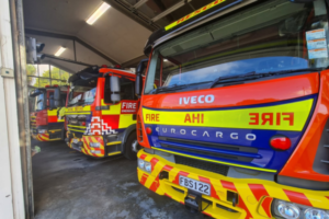 Three red and yellow fire appliances parked inside Porirua Fire Station.