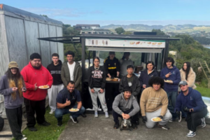 Porirua Whānau Centre Programmes Manager TJ Fermanis (front row, squatting) with a group of rangatahi taking part in the He Poutama Rangatahi work readiness programme, gathered around the programme's food truck in Cannons Creek.