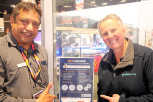 A Noel Leeming staff member and Porirua City Council representative point to a TechCollect NZ e-waste drop-off sign inside Noel Leeming Porirua.
