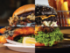 Collage showing four burgers, including a black-bun burger, a crispy fish burger and beef burgers with lettuce, bacon and fried toppings.